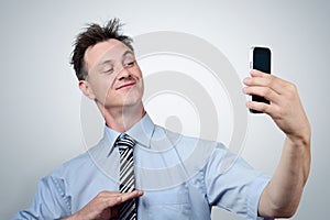 Funny businessman photographing himself on a smartphone