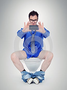 Funny businessman photographing himself in the toilet.