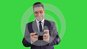 Funny businessman playing in game on the phone and winning on a Green Screen, Chroma Key.