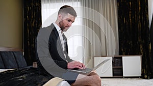 Funny businessman in shorts and suit working from hotel room on business trip