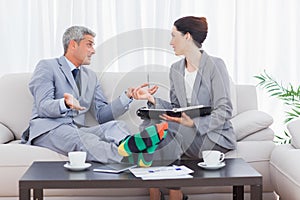 Funny businessman wearing stripey socks and talking with his col