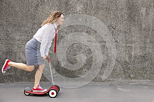 Funny businesswoman riding scooter outdoor