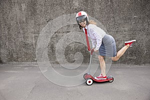 Funny businesswoman riding scooter outdoor