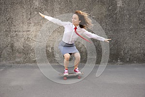 Funny businesswoman riding skateboard outdoor