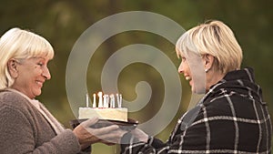 Funny cake joke, happy senior woman congratulating female friend on birthday