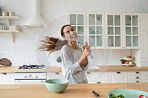 Funny carefree mixed race young girl singing song in whisk.