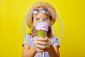 Funny caucasian child girl with ice cream, close-up shot on yellow isolated background.