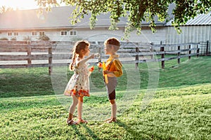 Funny Caucasian children girl and boy blowing soap bubbles in park