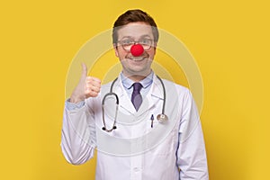 Funny caucasian doctor with clown red nose smiling at camera