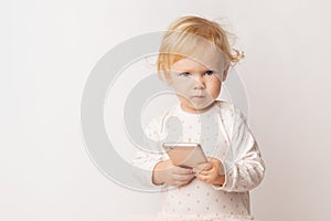 Funny Caucasian little girl feeling angry as she lost game. Mad female child having displeased look because of low battery on cell