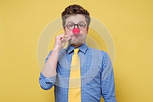 Funny caucasian man in glasses and clown nose making gesture with hand, zipping lips