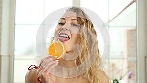 Funny caucasian woman licking orange slice