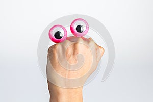 Funny character creature hiding behind female hand with googly e