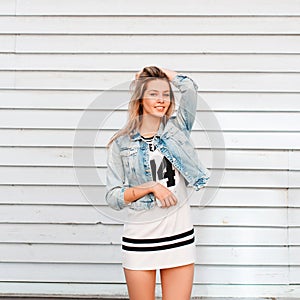 Funny charming happy young woman in fashionable summer clothes posing outdoors near a wooden vintage wall. Cheerful girl enjoys