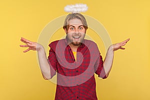 Funny cheerful bearded guy with saint nimbus over head raising hands as wings flying up, pretending angel, looking at camera