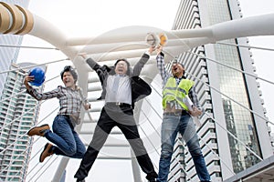 Funny cheerful businessman and engineers jumping in air and raising arms with job to success