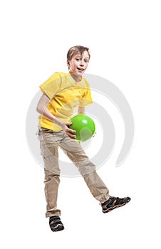 Funny cheerful child in yellow t-shirt jumping with a ball