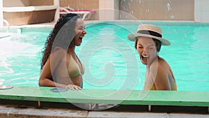 Funny cheerful girlfriends multiracial arabian caucasian women splashing water in pool having fun summer holidays