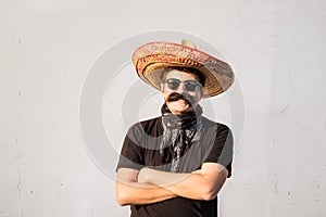 Funny and cheerful man dressed up in traditional mexican sombrero, false moustache, bandana and sunglasses. Festival or halloween
