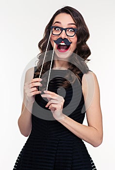 Funny cheerful woman having fun using glasses and moustache props