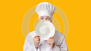 Funny Chef Guy Peeking Out Of Plate Standing In Studio, Panorama