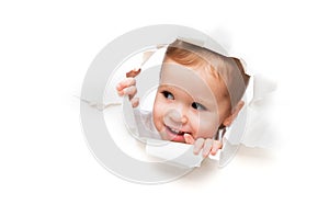Funny child baby girl peeping through hole in an empty white p