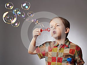 Funny child blowing soap bubbles. little boy