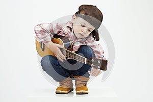 Funny child boy with guitar.ukulele guitar. fashionable country boy playing music