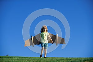 Funny child boy playing with plane wings outdoors. Cute boy playing pilot and dreaming of becoming a aviator pilot. Kid