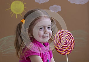 Funny child with candy lollipop, happy little girl eating big sugar lollipop, kid eat sweets.