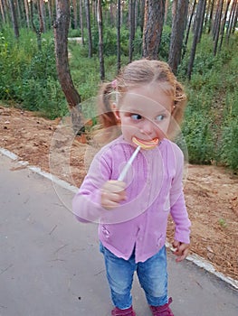 Funny child with candy lollipop, happy little girl eating big sugar lollipop, kid eat sweets. surprised child with candy