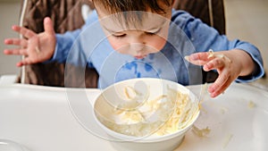 Funny child eating a grated apple with his hand from a plate, close-up.