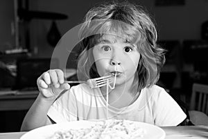 Funny child eating pasta, spaghetti. Kids face, little boy portrait.