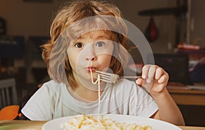 Funny child eating pasta, spaghetti. Kids face, little boy portrait.