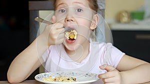 Funny child eats omelet in several pieces close up. Baby girl is hungry and has great appetite. Concept of home food and