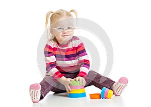 Funny child in eyeglases playing colorful pyramid photo