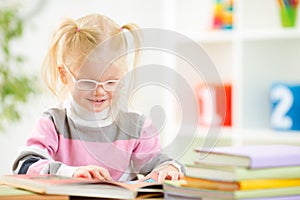 Funny child in eyeglases reading book at home photo