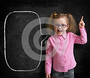 Funny child in eyeglasses standing near school chalkboard