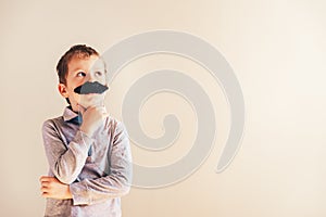 Funny child with fake mustache gesturing like an adult man, maturity and business concept photo