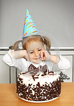 Funny child girl with birthday hat and cake