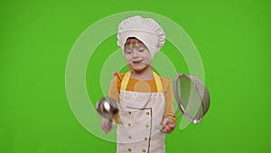 Funny child girl cook chef baker in apron and hat dancing with sieve and ladle, fooling around