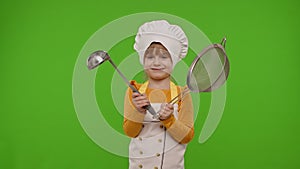 Funny child girl cook chef baker in apron and hat dancing with sieve and ladle, fooling around