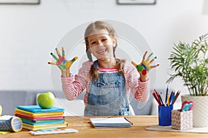 Funny child girl draws laughing shows hands dirty with paint