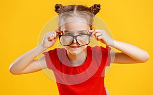 Funny child girl in glasses on colored background