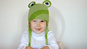 Funny child girl in green hat smiling and laughing. Cute happy baby playing and looking at camera. Closeup portrait