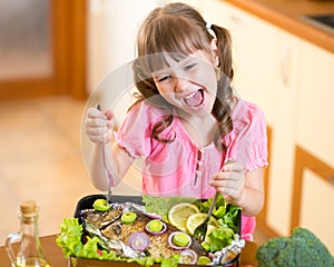 Funny child girl and grilled fish. Healthy eating