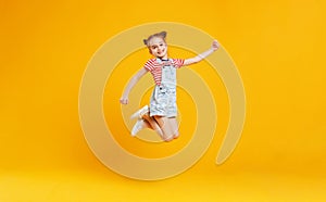 Funny child girl jumping on colored yellow background