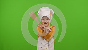 Funny child girl kid dressed cook chef baker in apron and hat dancing, fooling around, making faces