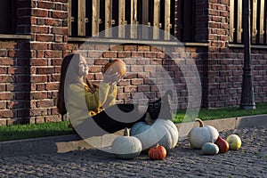 Funny child girl in orange pullover for Halloween with pumpkin and on a dark brick background