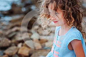 Funny child girl playing with water splash on the beach. Traveling on summer vacation.